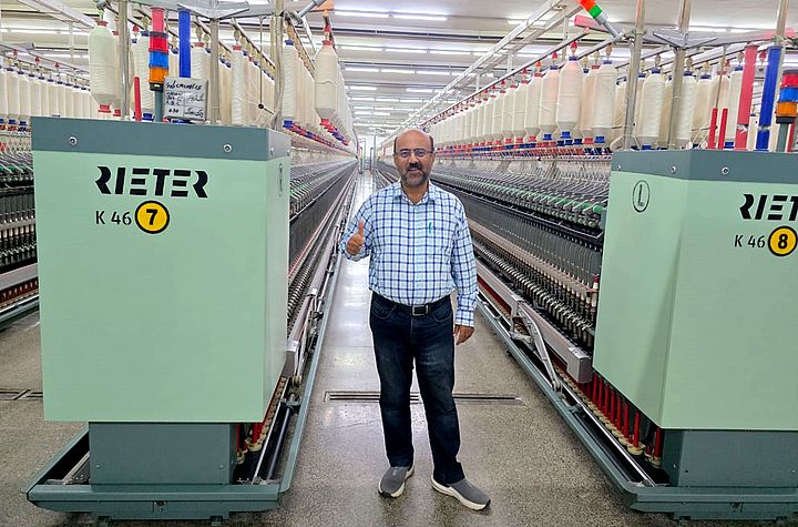 Malik Asad Ullah, Technical Director of Masood Fabrics Limited (Spinning Unit) standing in front of Rieter compact-spinning K 46 machine