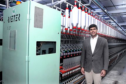 Balamukunthan Sivakumar, Joint Managing Director, Rajaguru Spinning Mills Pvt. Ltd. stands next to the ring spinning machine G 37 equipped with COMPACTapron.