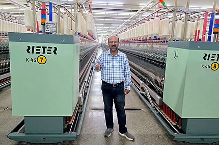 Malik Asad Ullah, Technical Director of Masood Fabrics Limited (Spinning Unit) standing in front of Rieter compact-spinning K 46 machine