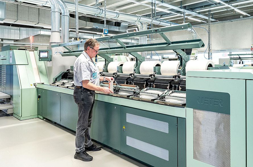 Interior view of the Spin Center at the Rieter Innovation Center in Winterthur, Switzerland. In the foreground, a Rieter expert works on a comber.